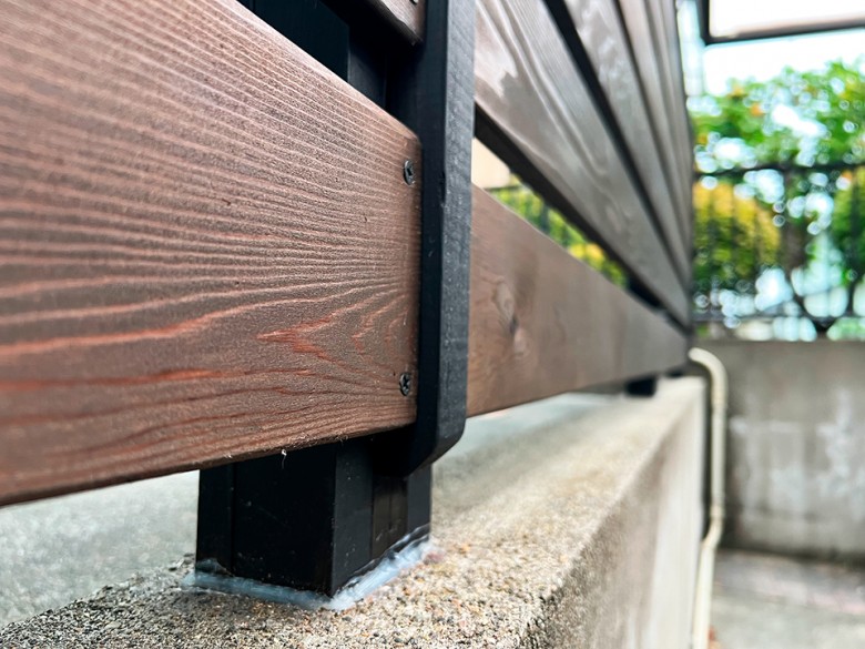 既存のアルミの支柱を特注のレッドシダーでコの字に包み込んだ柱に横張のフェンス材をＤＩＹで取付
