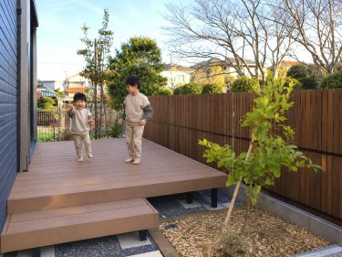 木製目隠しフェンス（メッシュフェンス用）を設置した庭で、周囲の視線を気にせず子どもたちがウッドデッキで遊ぶ施工事例