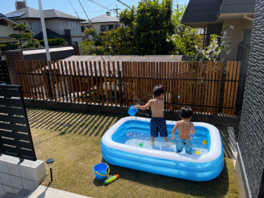 木製目隠しフェンス（メッシュフェンス用）を設置した庭で、外からの視線を気にせず子どもたちが家庭用プールで水遊びを楽しむ施工事例