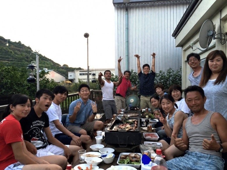 サイプレスでリフォームしたウッドデッキの低いテーブルを囲み、お盆に家族みんなでBBQを楽しむ河野様ご家族